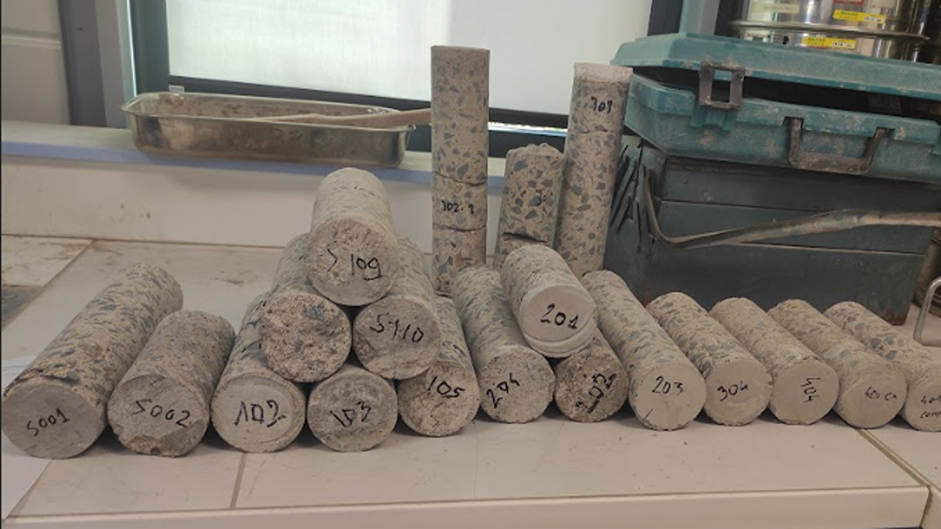 Des échantillons de forages en béton disposés sur une table, identifiés par des numéros, dans un environnement de bureau d'études à Nantes.