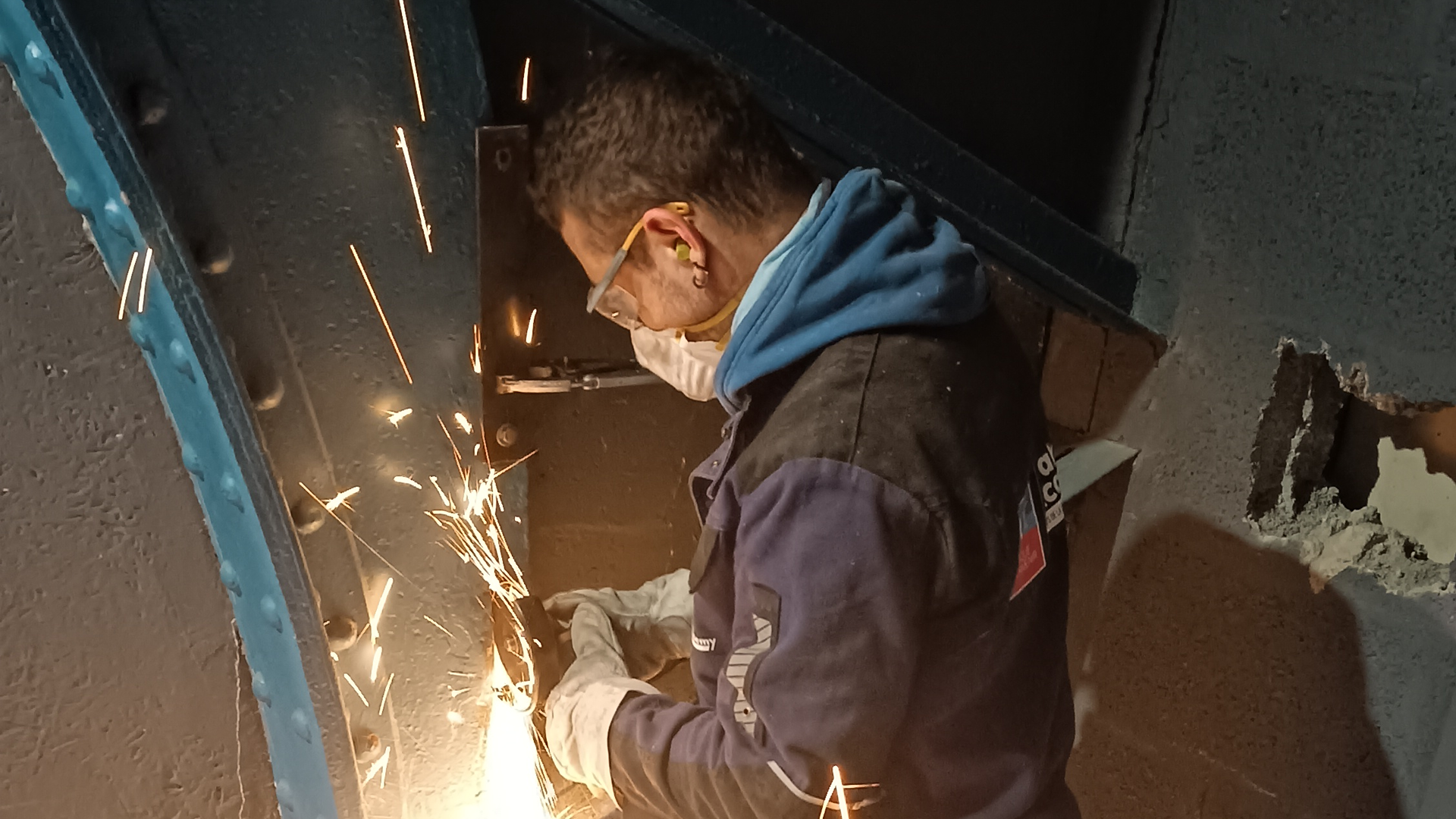 Un technicien effectue des travaux d'Auscultation de l'Existant avec des étincelles visibles à Nantes, dans un environnement de bureau d'études.